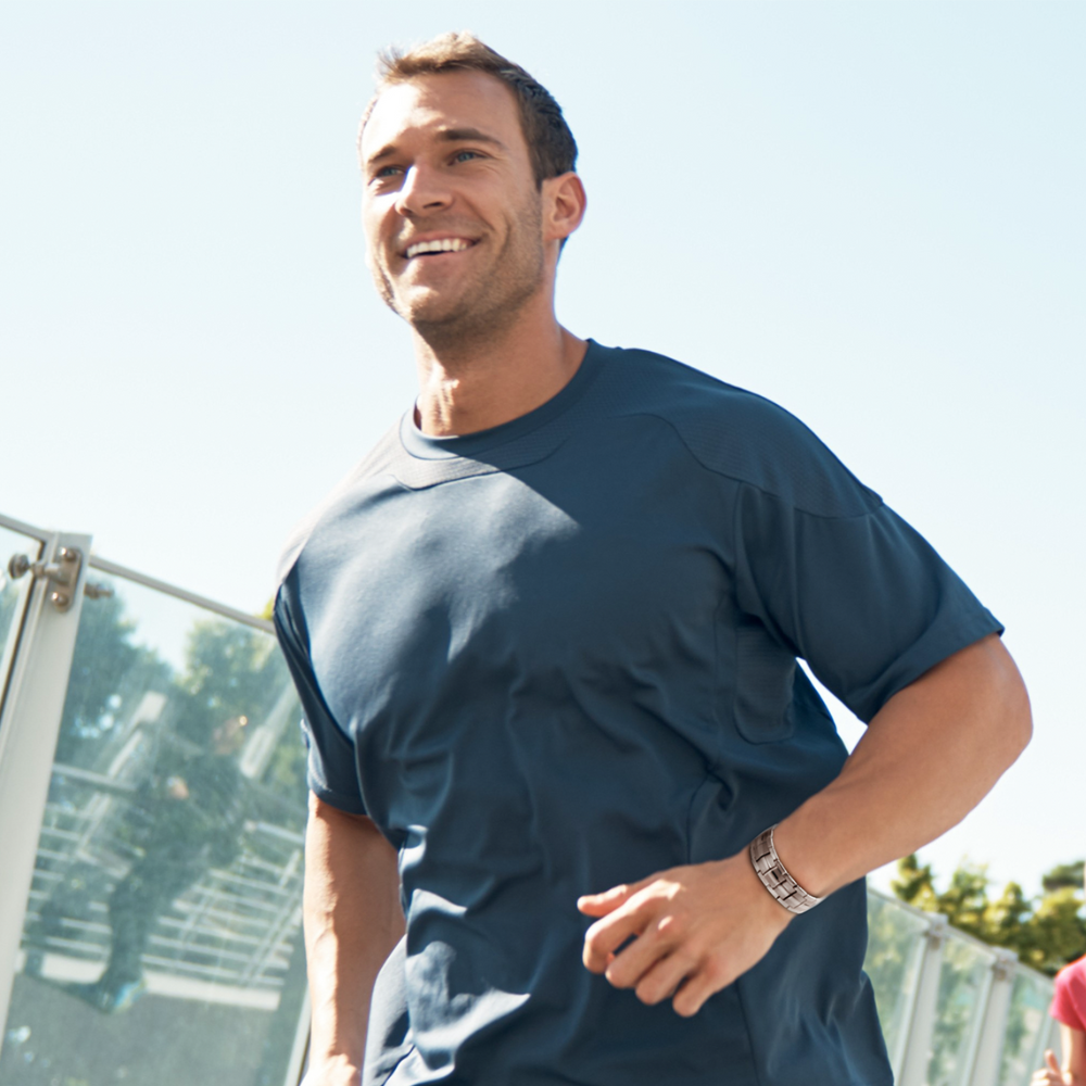 Man wearing a copper magnetic bracelet while stretching outdoors – magnetic therapy jewellery for pain relief